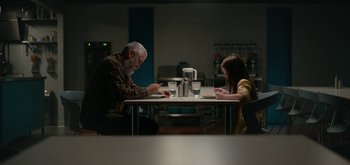 Movie still from “The Midnight Sky” (2020), directed by George Clooney – A man and a woman sitting at a dinner table; Wide shot, High angle