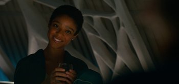 Movie still from “The Midnight Sky” (2020), directed by George Clooney – A woman smiling while holding a glass of wine; Close Up shot, Over the shoulder angle