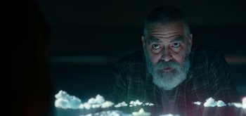 Movie still from “The Midnight Sky” (2020), directed by George Clooney – An older man with grey hair and a beard looking at the camera; Close Up shot, Low angle