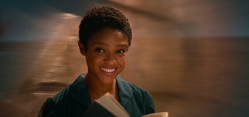 Movie still from “The Midnight Sky” (2020), directed by George Clooney – A woman smiling while holding a book; Close Up shot, Low angle