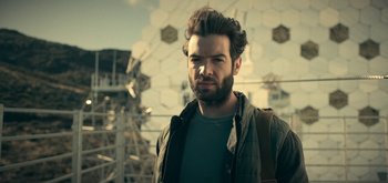 Movie still from “The Midnight Sky” (2020), directed by George Clooney – A man with a beard is standing in front of a ferris wheel; Close Up shot, Low angle