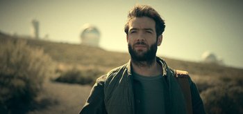 Movie still from “The Midnight Sky” (2020), directed by George Clooney – A man with a beard is standing in a field; Close Up shot, Low angle