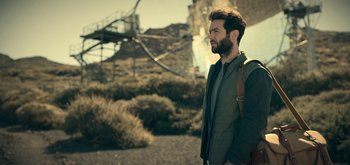 Movie still from “The Midnight Sky” (2020), directed by George Clooney – A man with a beard is standing on the beach; Medium shot, Low angle
