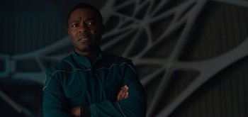 Movie still from “The Midnight Sky” (2020), directed by George Clooney – A man with his arms crossed in front of a wall; Close Up shot, Over the shoulder angle