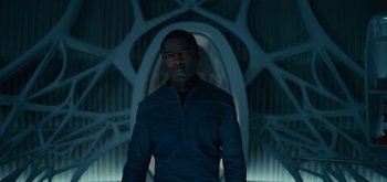 Movie still from “The Midnight Sky” (2020), directed by George Clooney – A man standing in the dark in front of an archway; Medium shot, Low angle