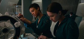 Movie still from “The Midnight Sky” (2020), directed by George Clooney – Two women sitting at a table looking at a tablet computer; Medium shot, Over the shoulder angle