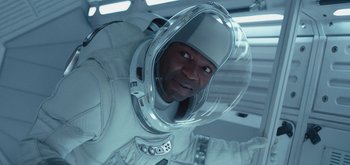 Movie still from “The Midnight Sky” (2020), directed by George Clooney – A man in a spacesuit is smiling for the camera; Close Up shot, Overhead angle