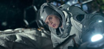 Movie still from “The Midnight Sky” (2020), directed by George Clooney – A woman in a spacesuit and a helmet looking into the distance; Medium shot, Overhead angle