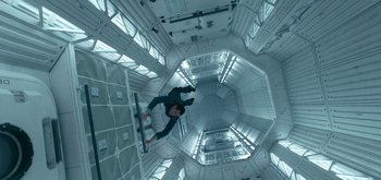 Movie still from “The Midnight Sky” (2020), directed by George Clooney – A man riding a skate board on a rail inside a building; Wide shot, Overhead angle