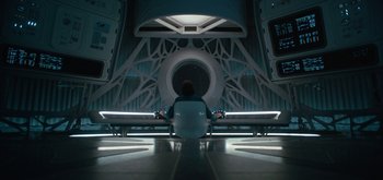 Movie still from “The Midnight Sky” (2020), directed by George Clooney – A man sitting in a chair in front of a wall; Wide shot, Overhead angle