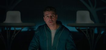 Movie still from “The Midnight Sky” (2020), directed by George Clooney – A man in a blue jacket is standing in a room; Medium shot, Low angle