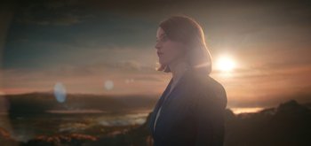 Movie still from “The Midnight Sky” (2020), directed by George Clooney – A woman standing in front of a sunset; Medium shot, Low angle