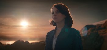 Movie still from “The Midnight Sky” (2020), directed by George Clooney – A woman standing in front of a sunset; Medium shot, Low angle