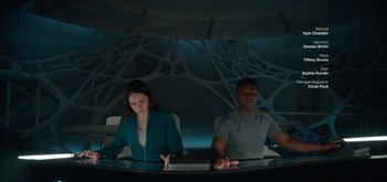 Movie still from “The Midnight Sky” (2020), directed by George Clooney – A man and a woman sitting in front of a computer screen; Medium shot, Low angle