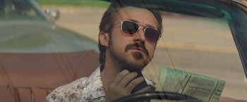 Movie still from “The Nice Guys” (2016), directed by Shane Black – A person in a car wearing sunglasses; Close Up shot, Low angle