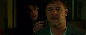 Movie still from “The Nice Guys” (2016), directed by Shane Black – A man holding a gun in front of a woman; Close Up shot, Over the shoulder angle