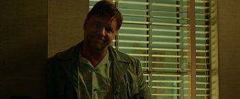 Movie still from “The Nice Guys” (2016), directed by Shane Black – A person wearing a jacket near a window; Close Up shot, Over the shoulder angle