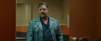 Movie still from “The Nice Guys” (2016), directed by Shane Black – A man wearing a leather jacket standing next to a wall; Medium shot, Over the shoulder angle