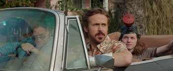 Movie still from “The Nice Guys” (2016), directed by Shane Black – A person sitting in a car; Close Up shot, Over the shoulder angle