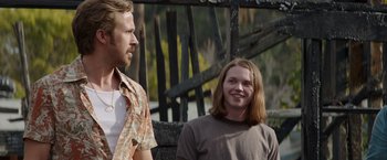 Movie still from “The Nice Guys” (2016), directed by Shane Black – A man standing next to a woman in a brown shirt; Medium shot, Over the shoulder angle