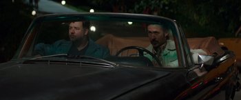 Movie still from “The Nice Guys” (2016), directed by Shane Black – A couple of men sitting in the back seat of a car; Medium shot, Over the shoulder angle