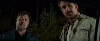 Movie still from “The Nice Guys” (2016), directed by Shane Black – A man standing next to another man in a forest; Close Up shot, Over the shoulder angle