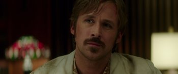Movie still from “The Nice Guys” (2016), directed by Shane Black – A person with a mustache; Close Up shot, Over the shoulder angle