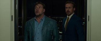 Movie still from “The Nice Guys” (2016), directed by Shane Black – A man and a woman standing next to each other in a room; Medium shot, Low angle