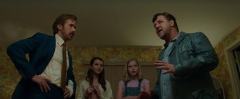 Movie still from “The Nice Guys” (2016), directed by Shane Black – A group of people standing in a living room talking; Medium shot, Low angle