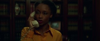 Movie still from “The Nice Guys” (2016), directed by Shane Black – A woman talking on a phone while wearing an orange shirt; Close Up shot, Low angle