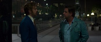 Movie still from “The Nice Guys” (2016), directed by Shane Black – Two men standing next to each other on a sidewalk; Medium shot, Over the shoulder angle