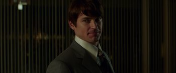 Movie still from “The Nice Guys” (2016), directed by Shane Black – A man wearing a suit and tie in front of a wall; Close Up shot, Over the shoulder angle