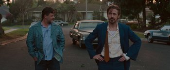 Movie still from “The Nice Guys” (2016), directed by Shane Black – Two men standing on the side of the street; Medium shot, Over the shoulder angle