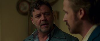 Movie still from “The Nice Guys” (2016), directed by Shane Black – A man in a blue shirt is talking to another man; Close Up shot, Over the shoulder angle