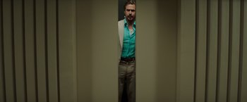 Movie still from “The Nice Guys” (2016), directed by Shane Black – A man standing in front of a mirror in front of a wall; Medium shot, Low angle