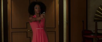 Movie still from “The Nice Guys” (2016), directed by Shane Black – A woman in a pink dress is holding a camera; Medium shot, Low angle