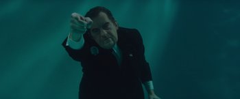 Movie still from “The Nice Guys” (2016), directed by Shane Black – A man in a suit and tie holding something in his hand; Medium shot, High angle