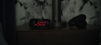 Movie still from “The Night Agent” (2023), created by Shawn Ryan – An alarm clock sitting on top of a wooden table; Extreme Close Up shot, High angle