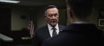 Movie still from “The Night Agent” (2023), created by Shawn Ryan – An older man wearing a suit and tie talking to a younger man; Close Up shot, Over the shoulder angle