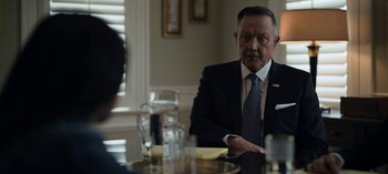 Movie still from “The Night Agent” (2023), created by Shawn Ryan – A man in a suit and tie sitting at a table; Close Up shot, Over the shoulder angle