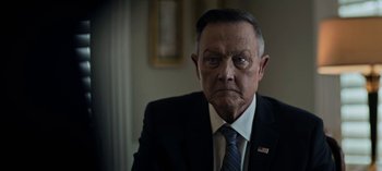 Movie still from “The Night Agent” (2023), created by Shawn Ryan – An older man wearing a suit and tie; Close Up shot, Low angle