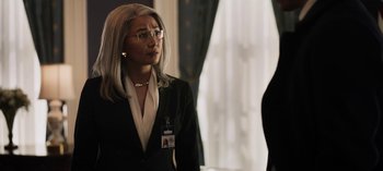 Movie still from “The Night Agent” (2023), created by Shawn Ryan – A woman in a black suit and glasses; Close Up shot, Over the shoulder angle