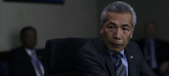 Movie still from “The Night Agent” (2023), created by Shawn Ryan – An older man in a suit and tie sitting in a chair; Close Up shot, Over the shoulder angle