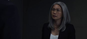 Movie still from “The Night Agent” (2023), created by Shawn Ryan – A woman in a black jacket and a white shirt; Close Up shot, Over the shoulder angle