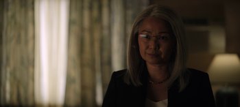 Movie still from “The Night Agent” (2023), created by Shawn Ryan – A woman wearing glasses and a black jacket; Close Up shot, Over the shoulder angle