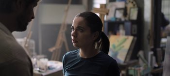 Movie still from “The Night Agent” (2023), created by Shawn Ryan – A woman with a ponytail is standing in front of a painting; Close Up shot, Low angle