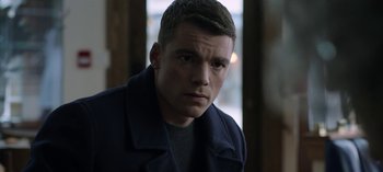 Movie still from “The Night Agent” (2023), created by Shawn Ryan – A man in a black jacket is looking at the camera; Close Up shot, Over the shoulder angle