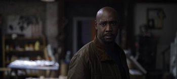 Movie still from “The Night Agent” (2023), created by Shawn Ryan – A man in a brown jacket standing in front of a wall; Close Up shot, Low angle