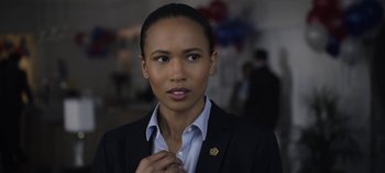 Movie still from “The Night Agent” (2023), created by Shawn Ryan – A woman in a black jacket and a blue shirt; Close Up shot, Over the shoulder angle