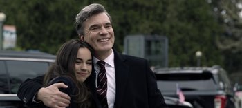 Movie still from “The Night Agent” (2023), created by Shawn Ryan – A man and a girl are smiling for the camera; Medium shot, Over the shoulder angle